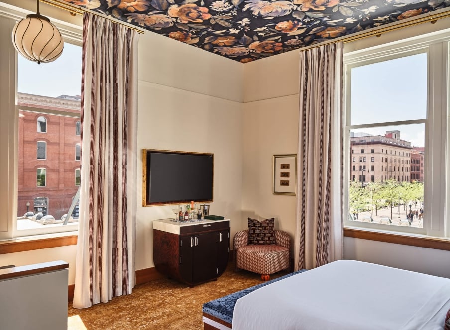 A television, bar cart and chair in the Deluxe Classic Guest room at the Crawford Hotel in Denver, Colorado.