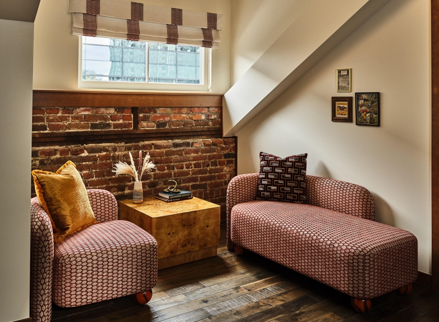 Seating area with a chair and chaise lounge in the Deluxe Loft Guest Room at the Crawford Hotel in Denver, Colorado.