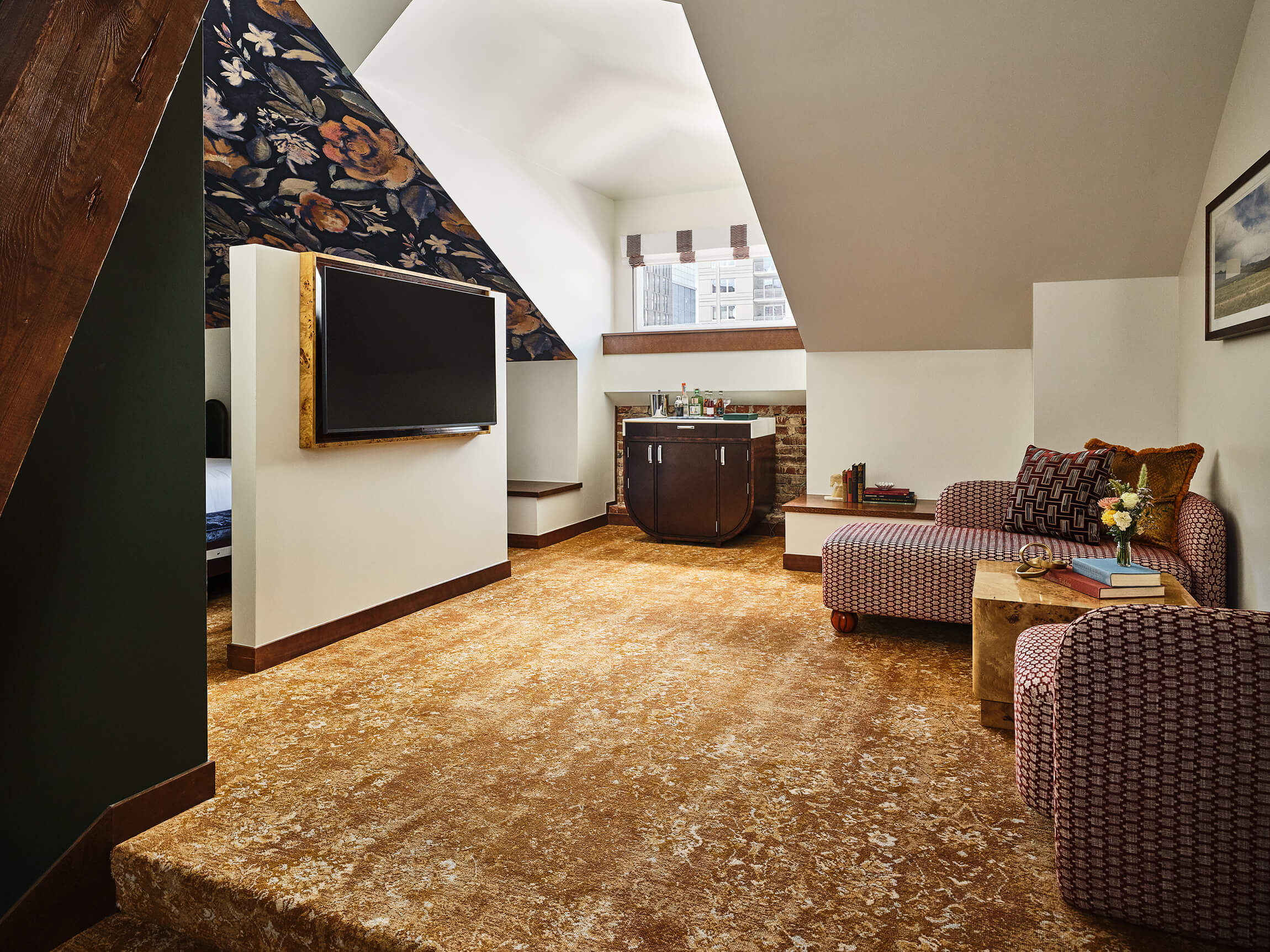 Living area with chair, chaise lounge, television, bar cart in the Premium Loft Guest Room at the Crawford Hotel in Denver, Colorado.