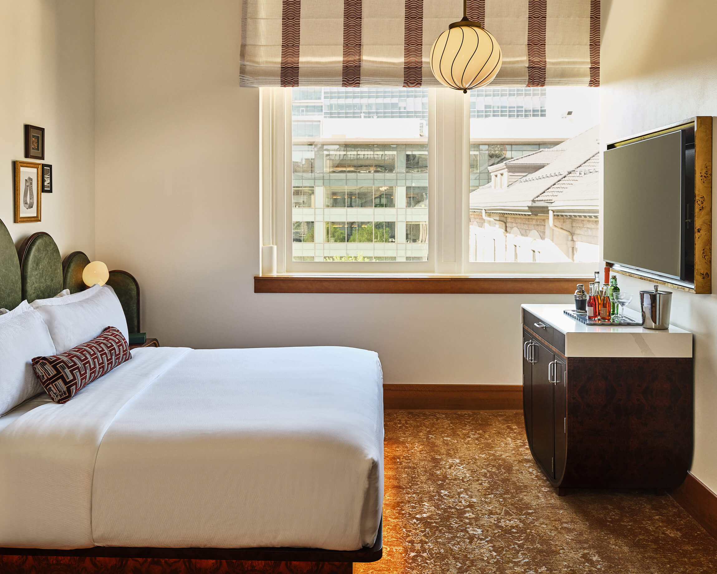 A king bed, bar cart and television in the Superior Classic Guest room at the Crawford Hotel in Denver, Colorado.