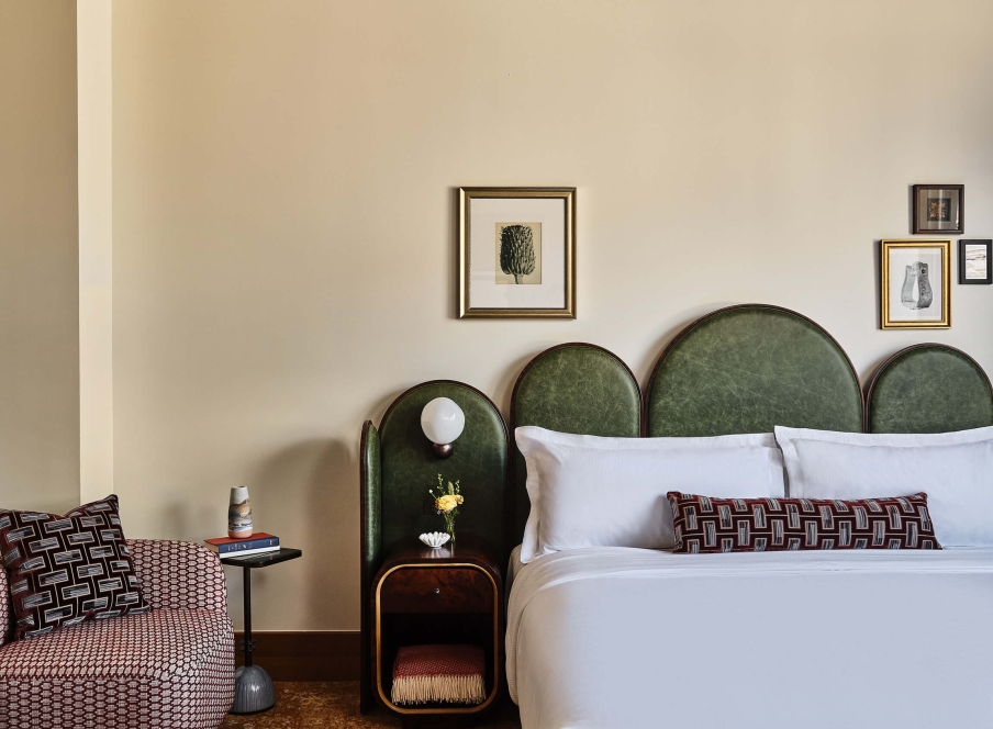 A king bed, chair, side table with fresh cut flowers and extra blanket in the Superior Classic Guest room at the Crawford Hotel in Denver, Colorado.