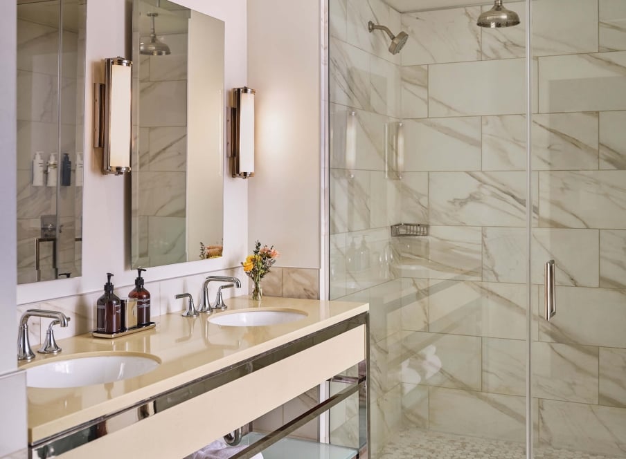 Double sinks and shower of the bathroom in the Premium Loft Guest Room at the Crawford Hotel in Denver, Colorado.