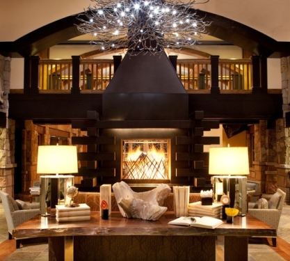 A grand fireplace in a lobby with ornate chandelier.