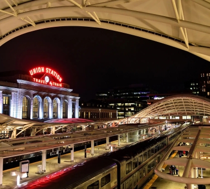A train inside Denver Union Station at night, the Union Station neon sign in the background.