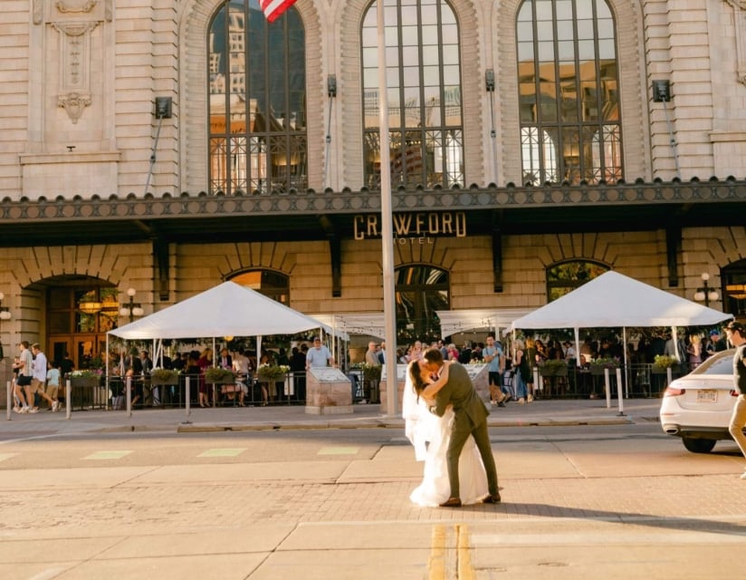 A bride and groom kiss dramatically in front of the Crawford Hotel in Denver, Colorado.