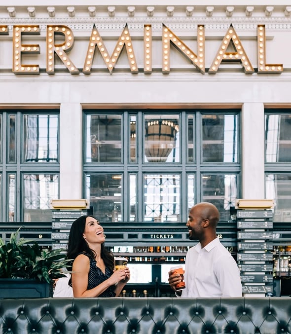 Two people laughing with coffee outside of Terminal Bar in Denver, Colorado.
