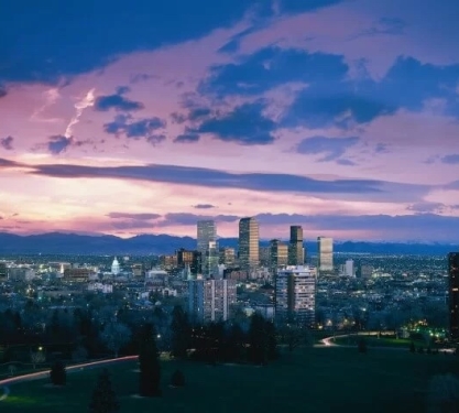 The skyline of Denver, Colorado with a dramatic purple and pink sunset in the background.