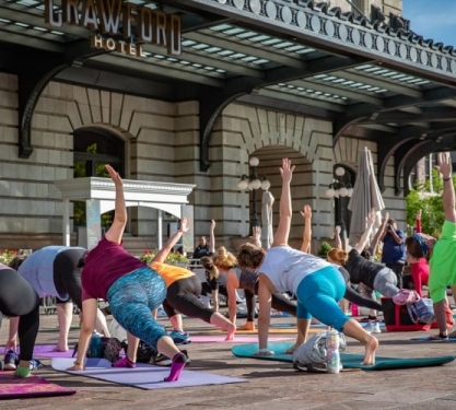 A group of people doing yoga outside in a city.