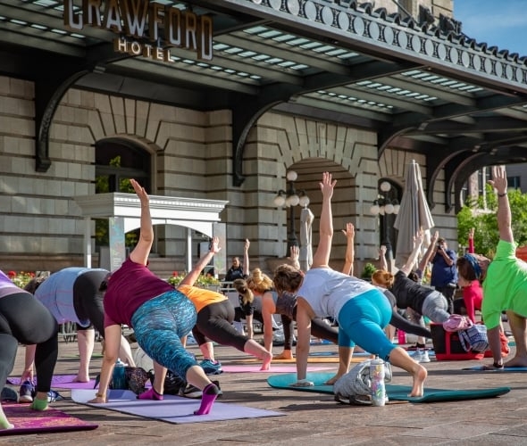 A group of people doing yoga outside in a city.