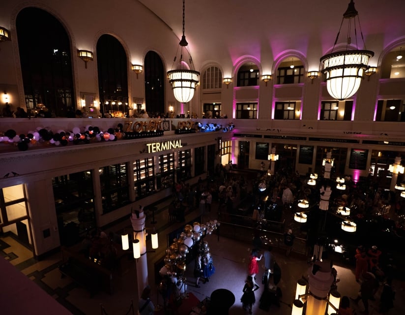 A party at Union Station, dim with ambient pink lighting. A group dances on the dance floor.