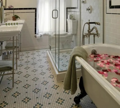 A filled clawfoot tub, prepared with rose petals in a hotel suite bathroom.