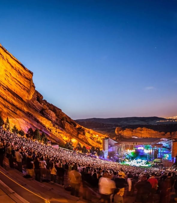 A concert taking place at dusk at Red Rocks Amphitheatre in Colorado.