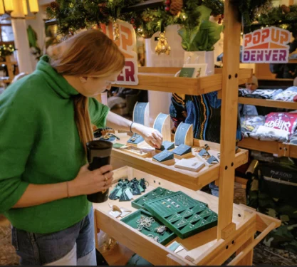 A woman shops for artisan jewelry in a market.