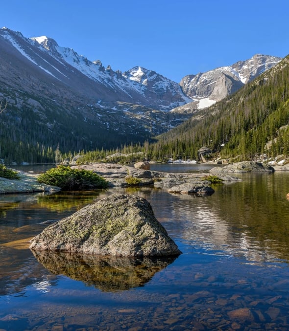 A calm river at the bottom of the Rocky Mountains on a sunny day.